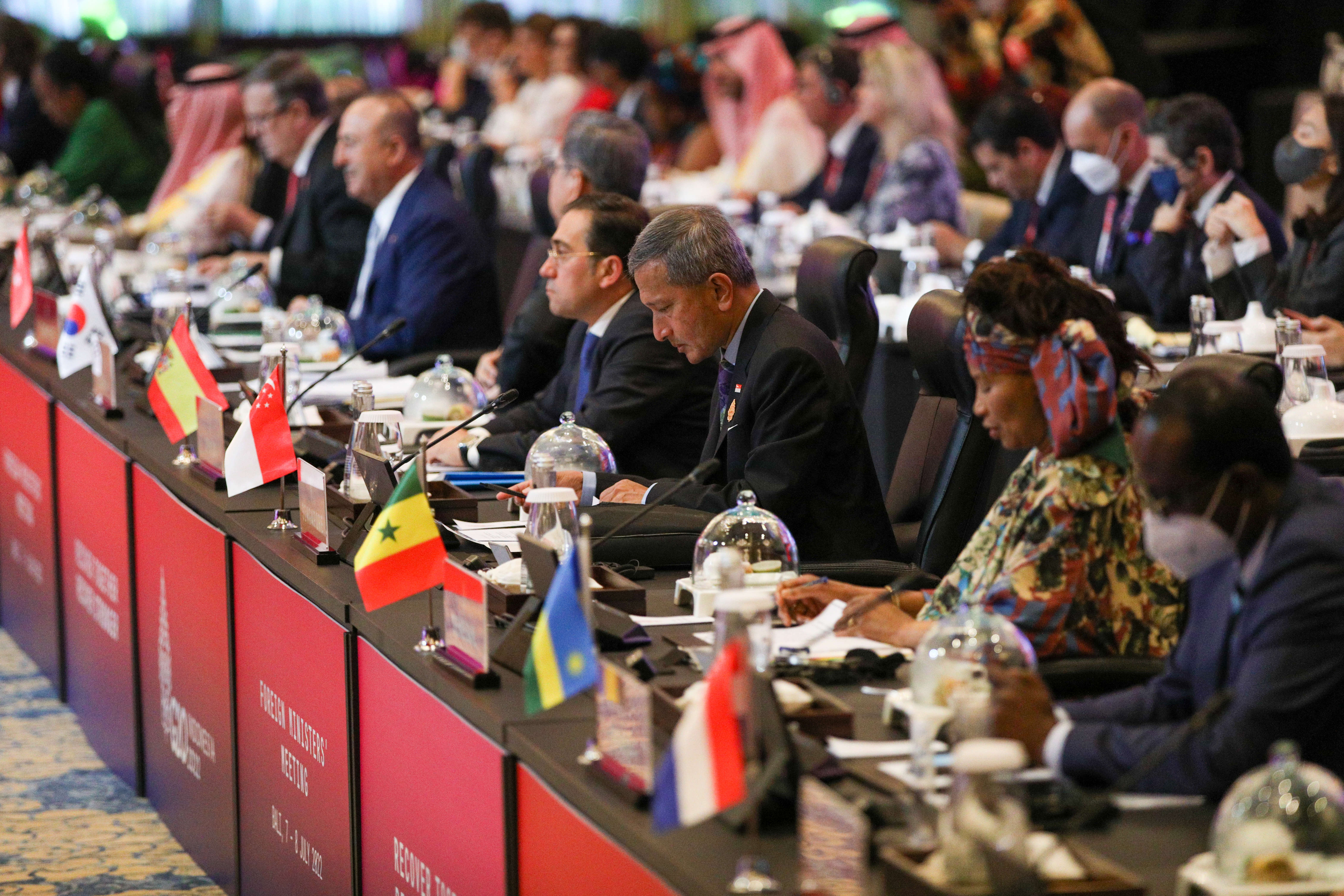 Two men in suits shake hands before flags of Singapore, Austria, and the European Union.